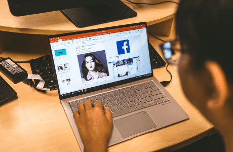 A person sitting at the desk and calling a friend via Facebook on their laptop.