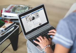 A woman typing something on Facebook on her laptop.